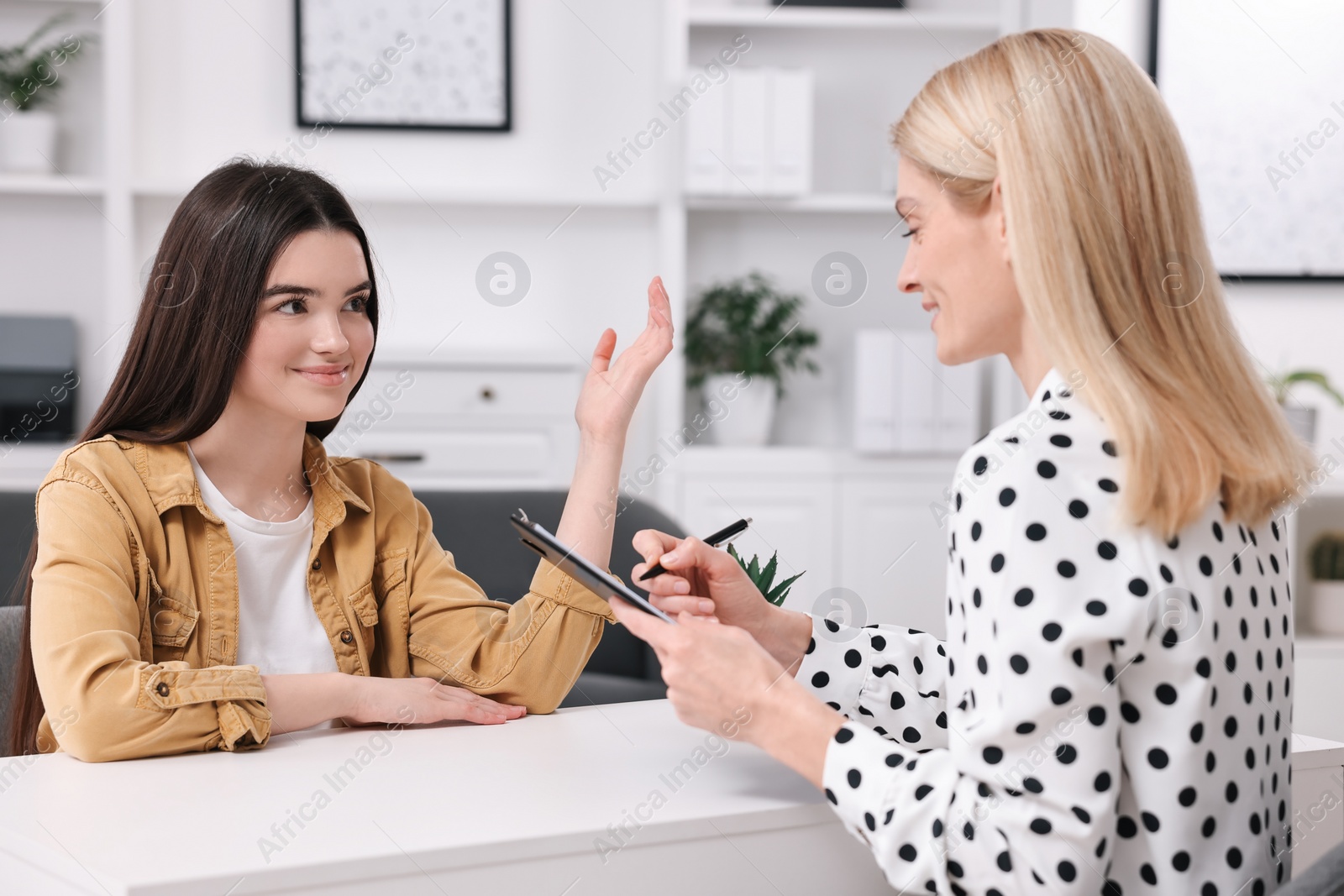 Photo of Psychologist working with teenage girl at table in office