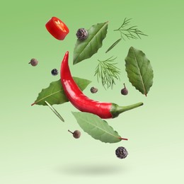 Image of Bay leaves, rosemary, dill, black and fresh red hot peppers falling on green gradient background