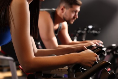 Photo of Woman and man training on exercise bikes in fitness club, closeup