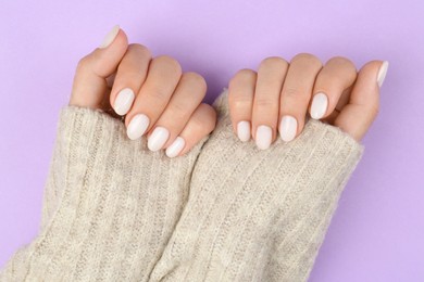 Photo of Woman with white polish on nails against violet background, top view