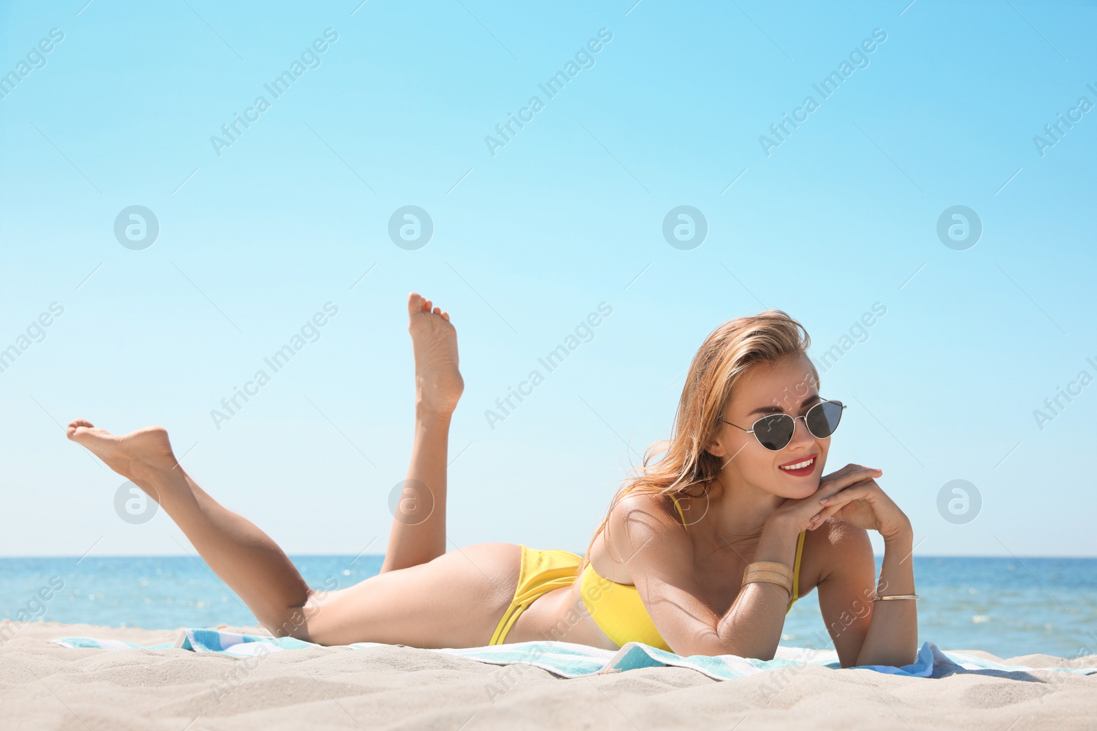 Photo of Beautiful woman with beach towel on sand near sea