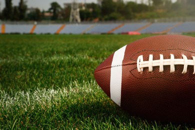 Photo of American football ball on green field grass in stadium, closeup