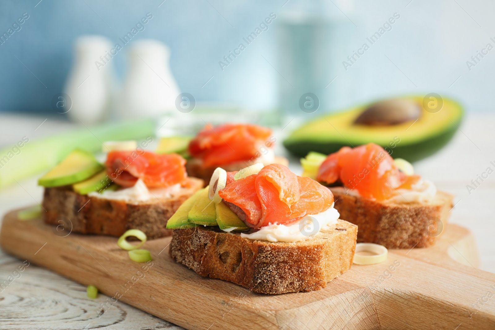 Photo of Tasty sandwiches with fresh sliced salmon fillet and avocado on wooden board, closeup