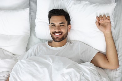 Portrait of happy man in bed, top view. Good morning