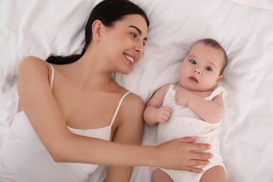 Photo of Young mother with her little baby on bed, top view