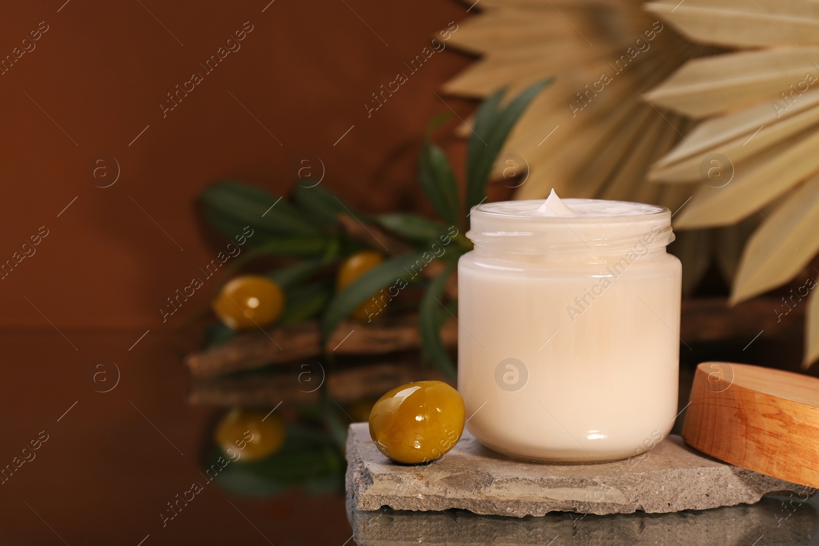 Photo of Jar of cream and olives on glass table, closeup. Space for text