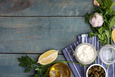 Tasty tartar sauce and ingredients on light blue wooden table, flat lay. Space for text