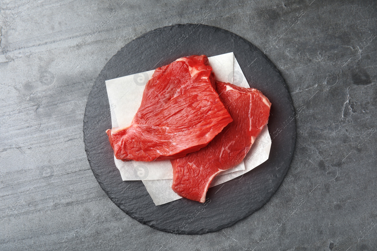 Photo of Fresh raw beef cut on grey table, top view