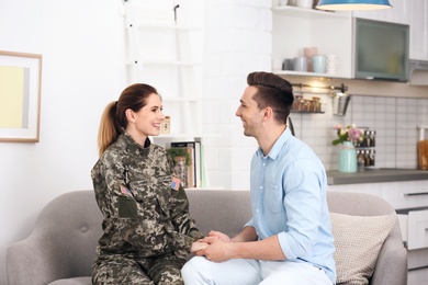 Woman in military uniform with her husband on sofa at home