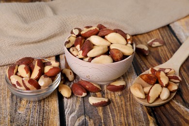 Bowls and spoon of delicious Brazil nuts on wooden table