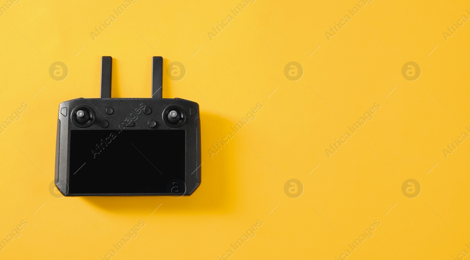 Photo of New modern drone controller on yellow background, top view. Space for text