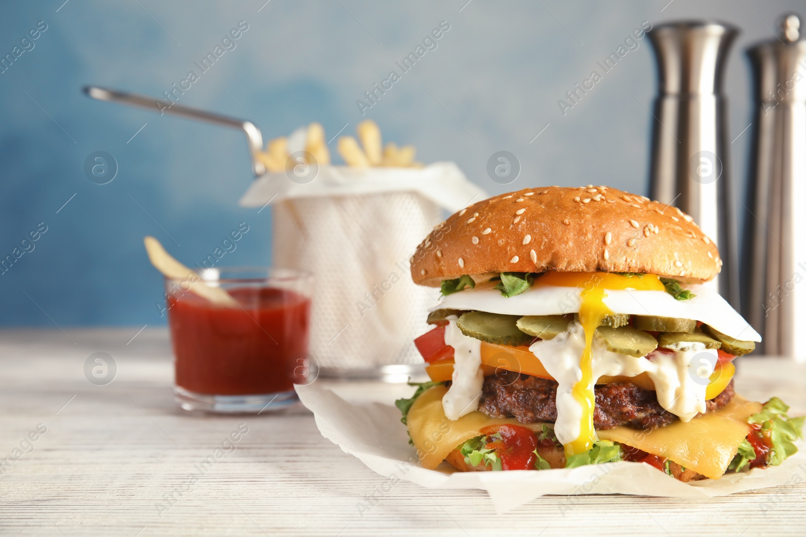 Photo of Tasty burger with fried egg on table against blurred background, space for text