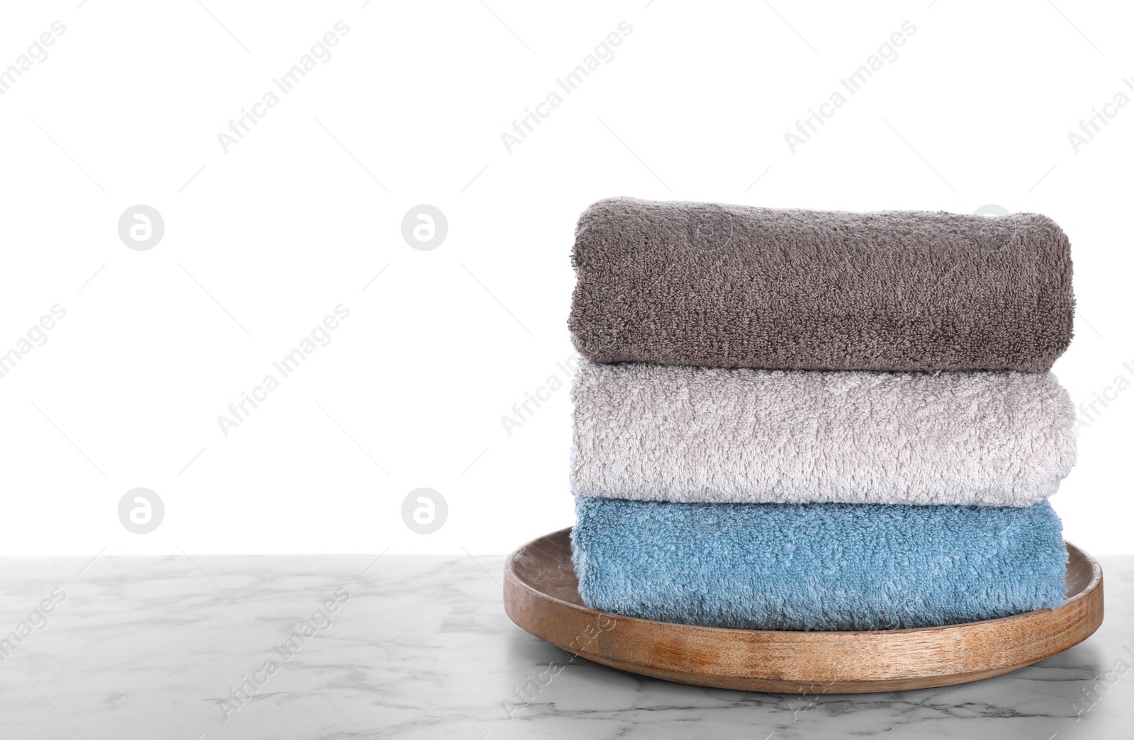 Photo of Fresh towels on marble table against white background. Space for text