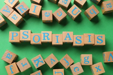 Word Psoriasis made of wooden cubes with letters on green background, flat lay