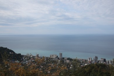 Picturesque view of city, green trees and sea under blue sky