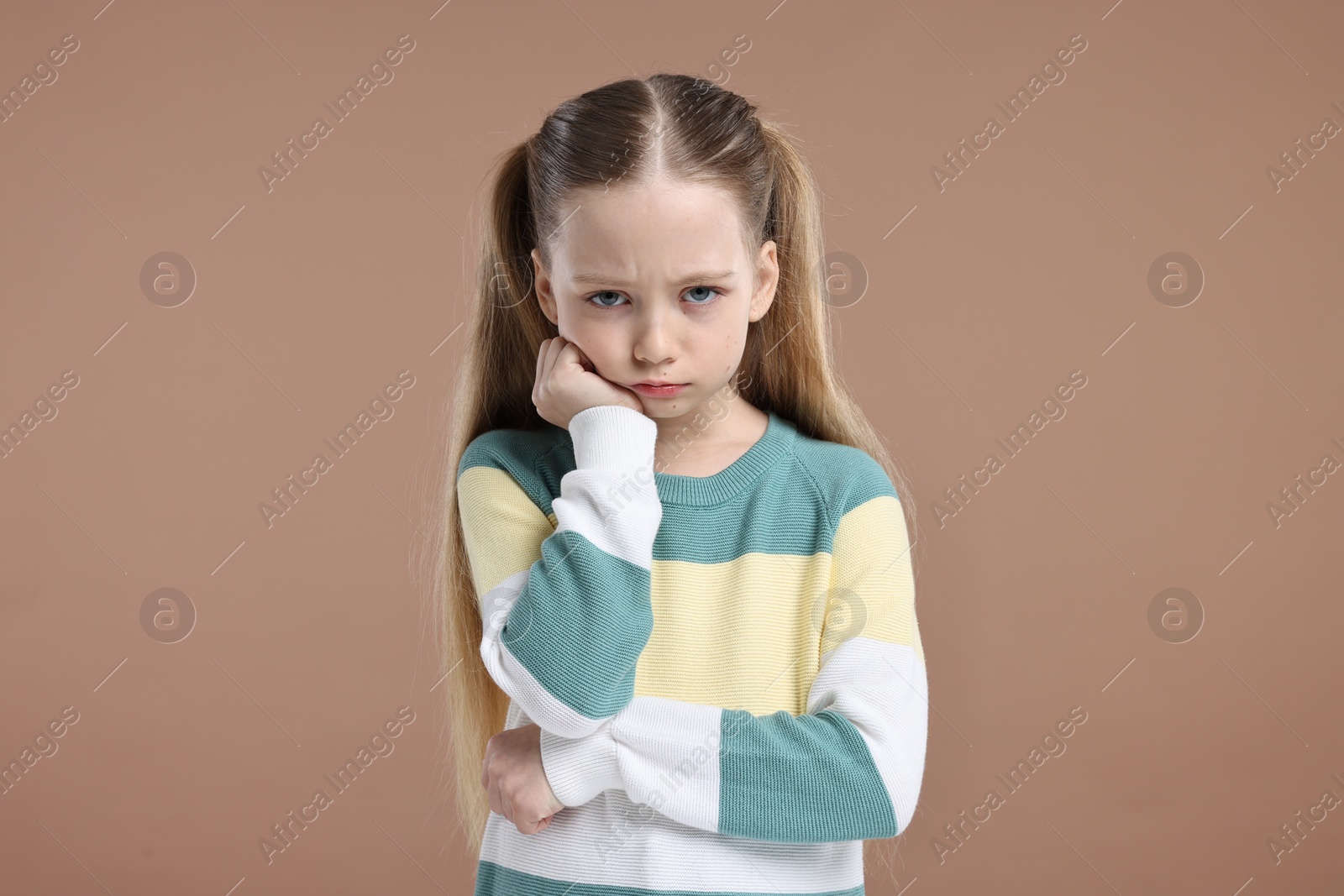 Photo of Portrait of sad girl on light brown background