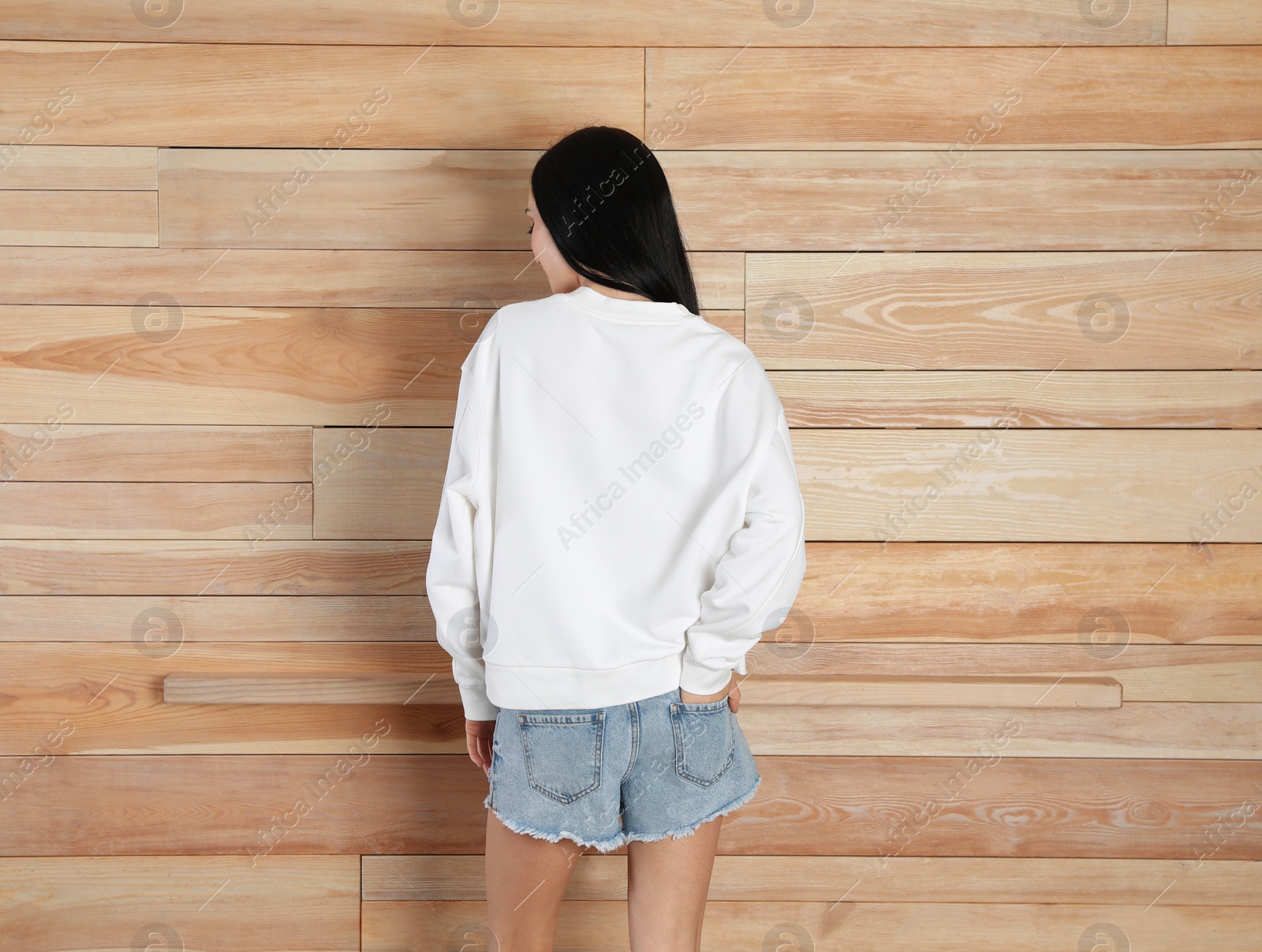 Photo of Young woman in sweater at wooden wall. Mock up for design