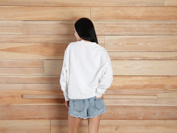 Young woman in sweater at wooden wall. Mock up for design