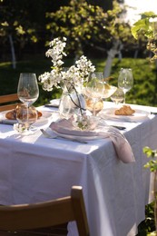 Photo of Beautiful table setting with spring flowers in garden on sunny day