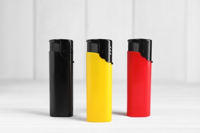 Photo of Stylish small pocket lighters on white wooden table