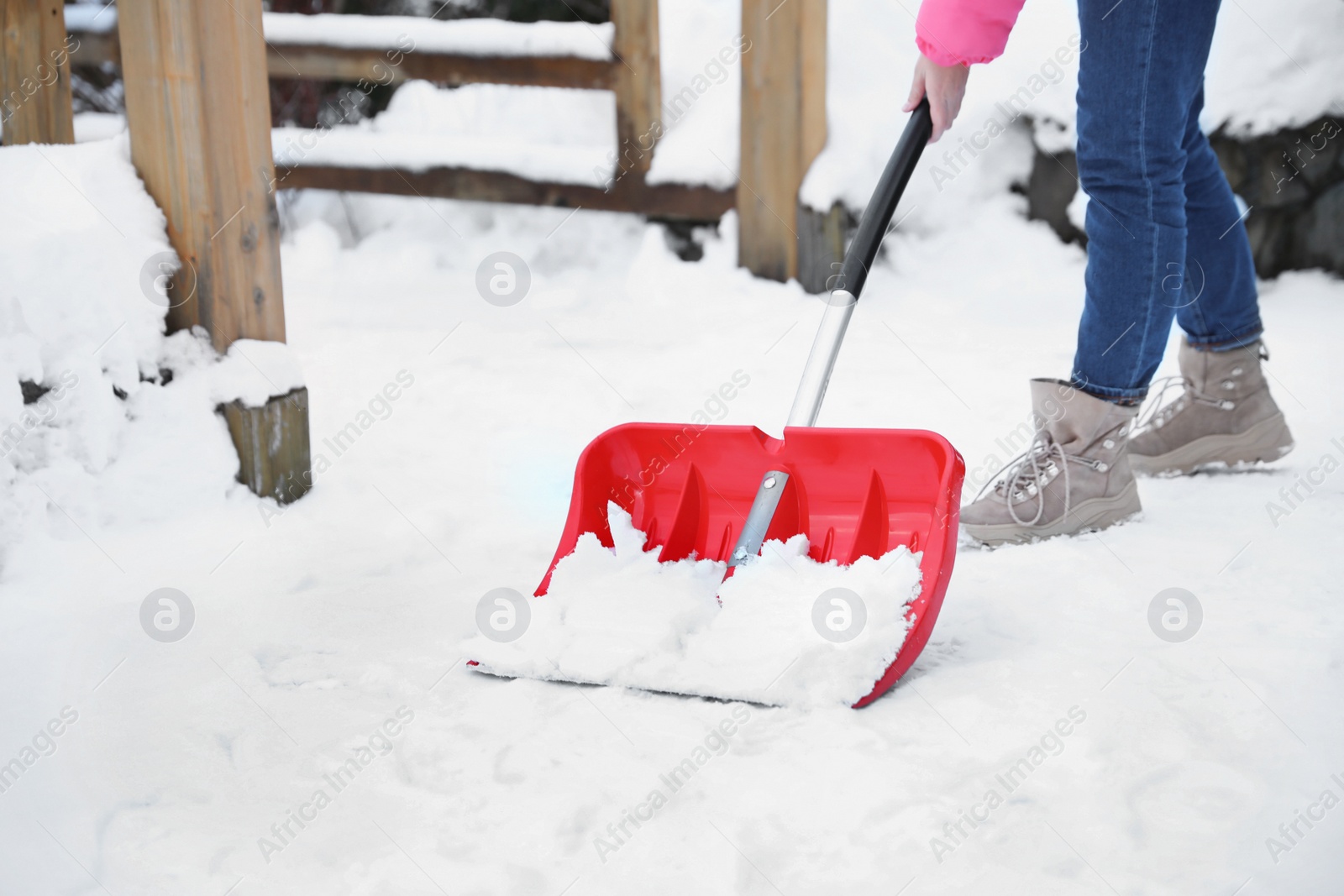 Photo of Woman cleaning snow with shovel outdoors on winter day, closeup