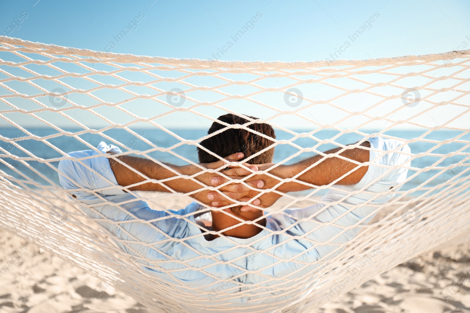 Photo of Man relaxing in hammock on beach. Summer vacation