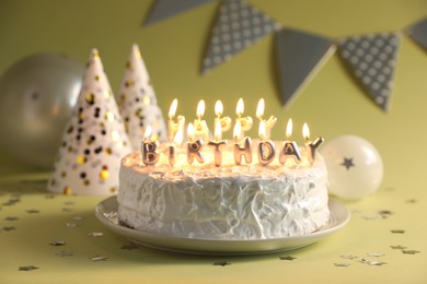 Photo of Tasty birthday cake with burning candles on green background, closeup