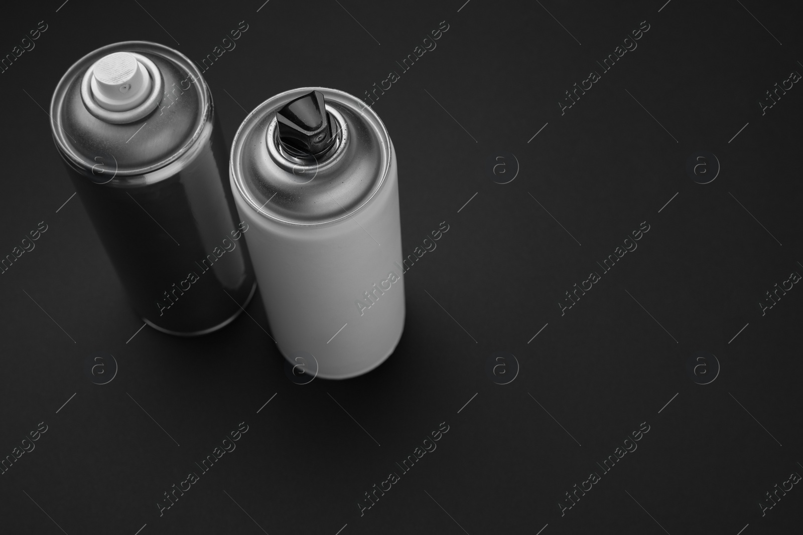 Photo of Cans of different graffiti spray paints on black background, above view. Space for text