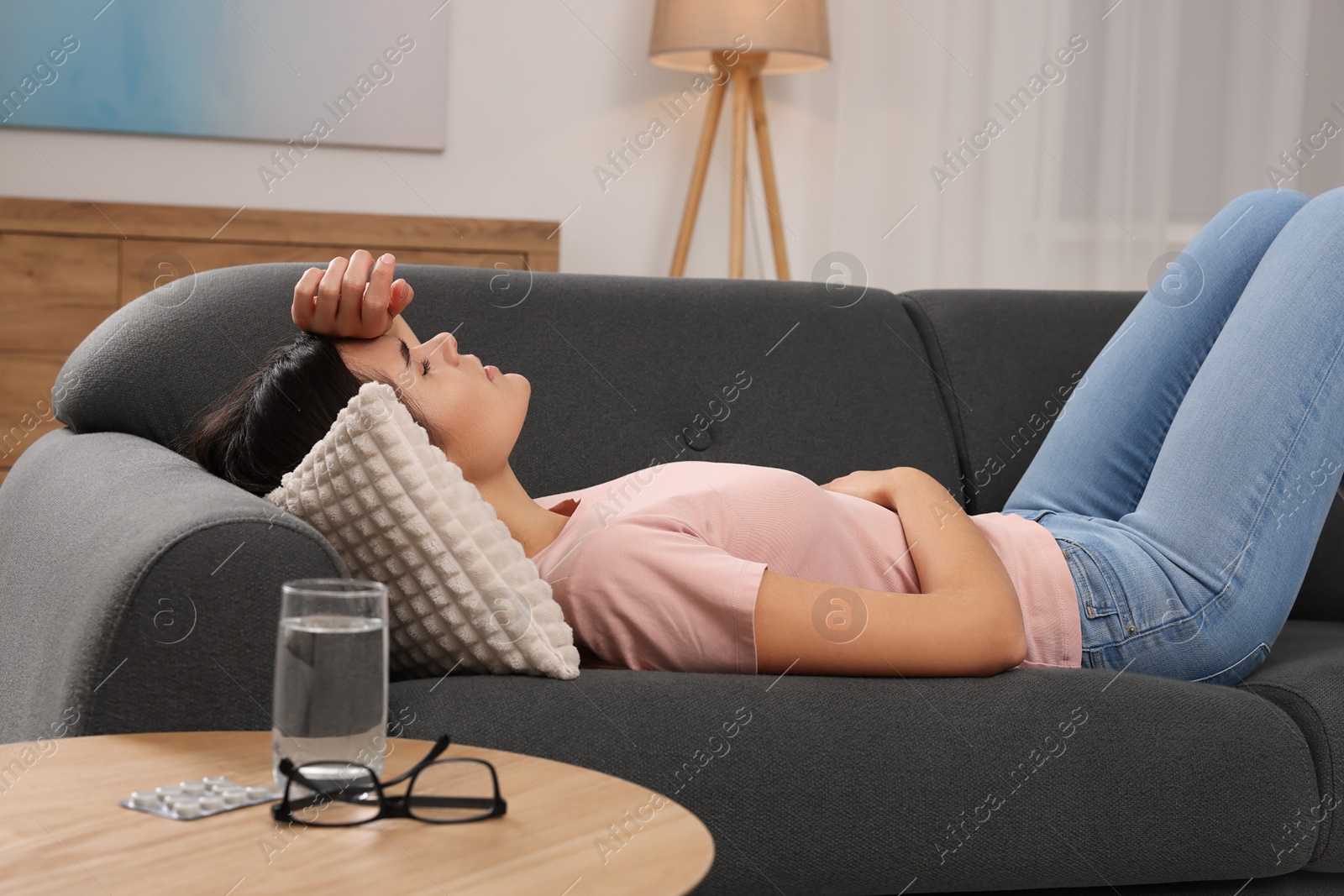 Photo of Sad woman suffering from headache on sofa indoors