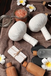 Herbal massage bags and other spa products on wooden table