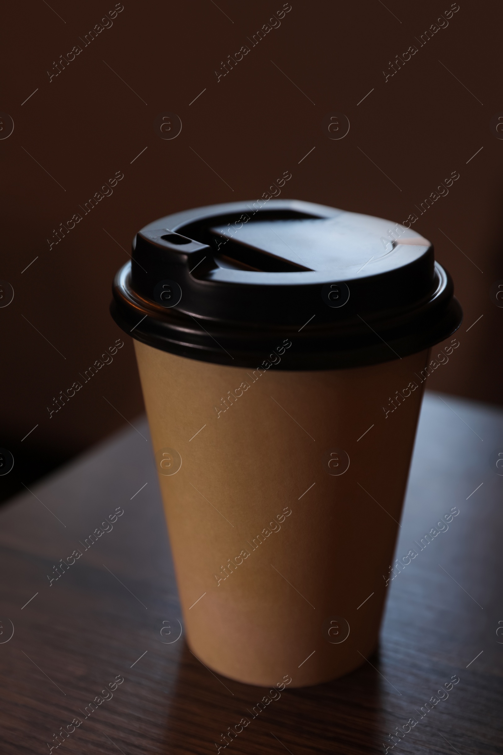 Photo of Takeaway coffee cup with plastic lid on wooden table indoors, closeup