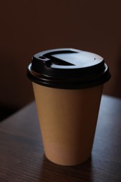 Takeaway coffee cup with plastic lid on wooden table indoors, closeup