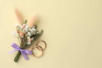 Small stylish boutonniere and rings on beige background, flat lay. Space for text