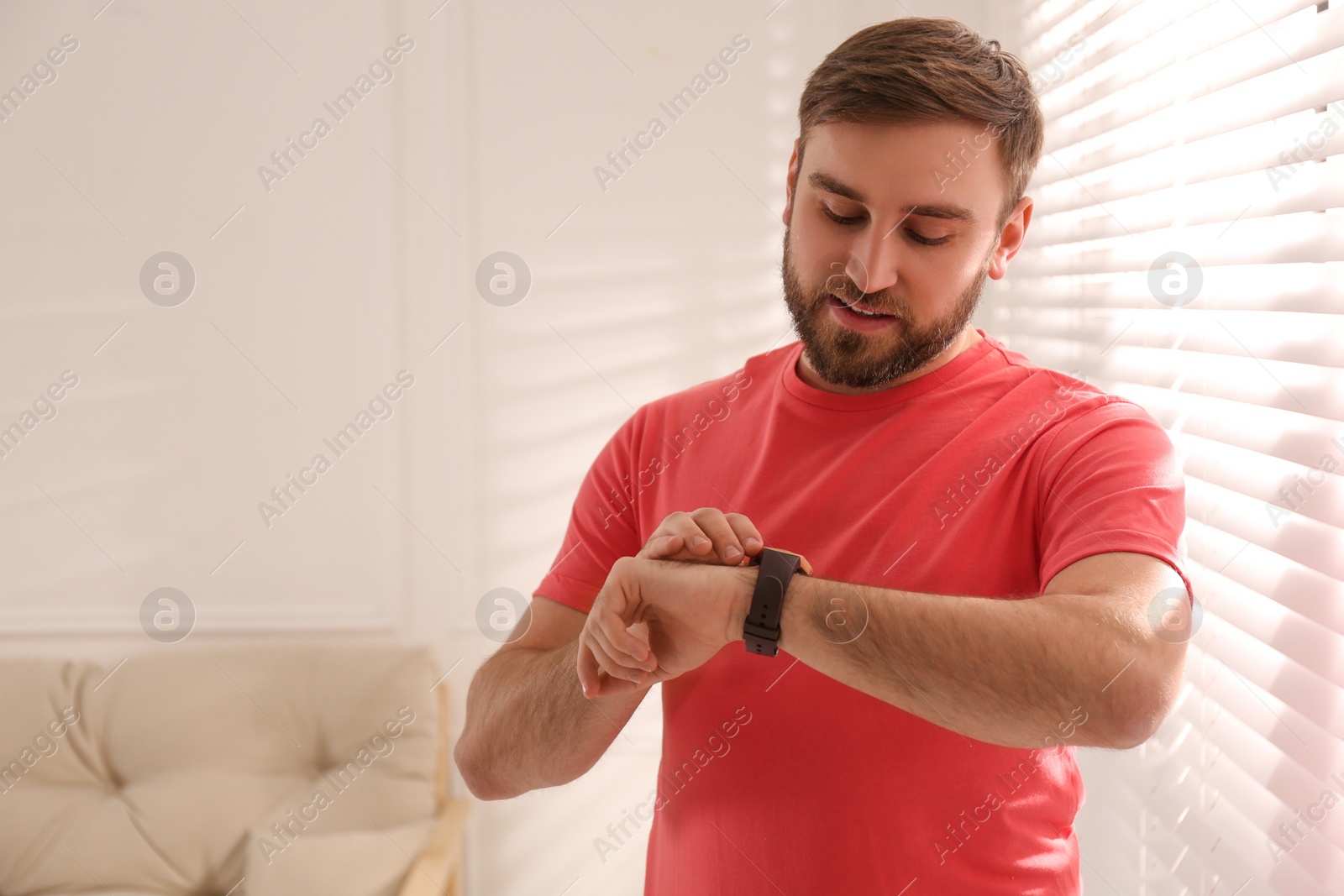 Photo of Young man using smart watch at home, space for text