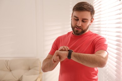 Photo of Young man using smart watch at home, space for text