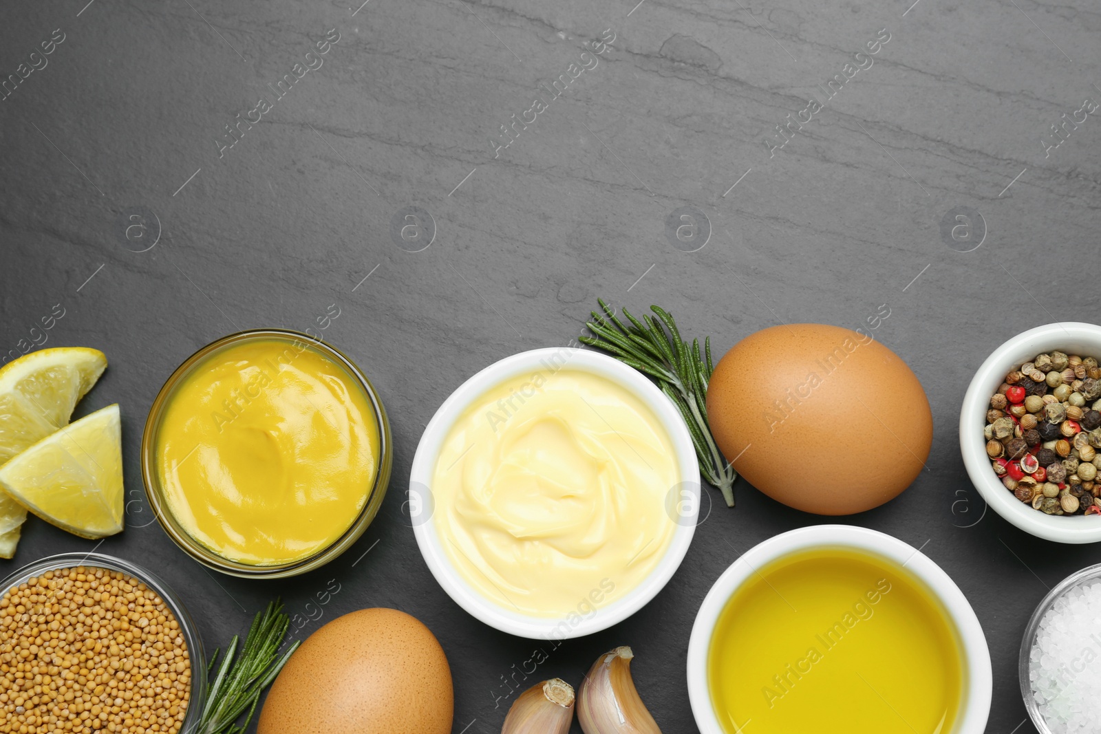 Photo of Delicious homemade mayonnaise, spices and ingredients on black table, flat lay. Space for text