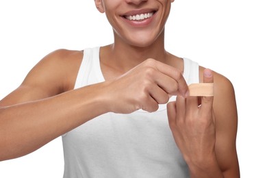 Photo of Man putting sticking plaster onto finger on white background, closeup