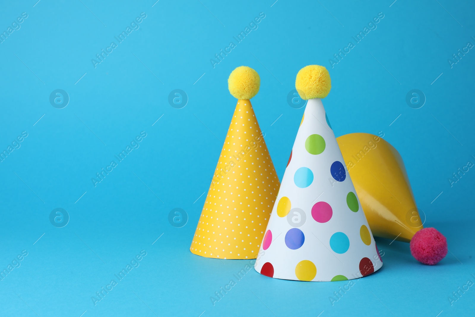 Photo of Colorful party hats on light blue background, space for text