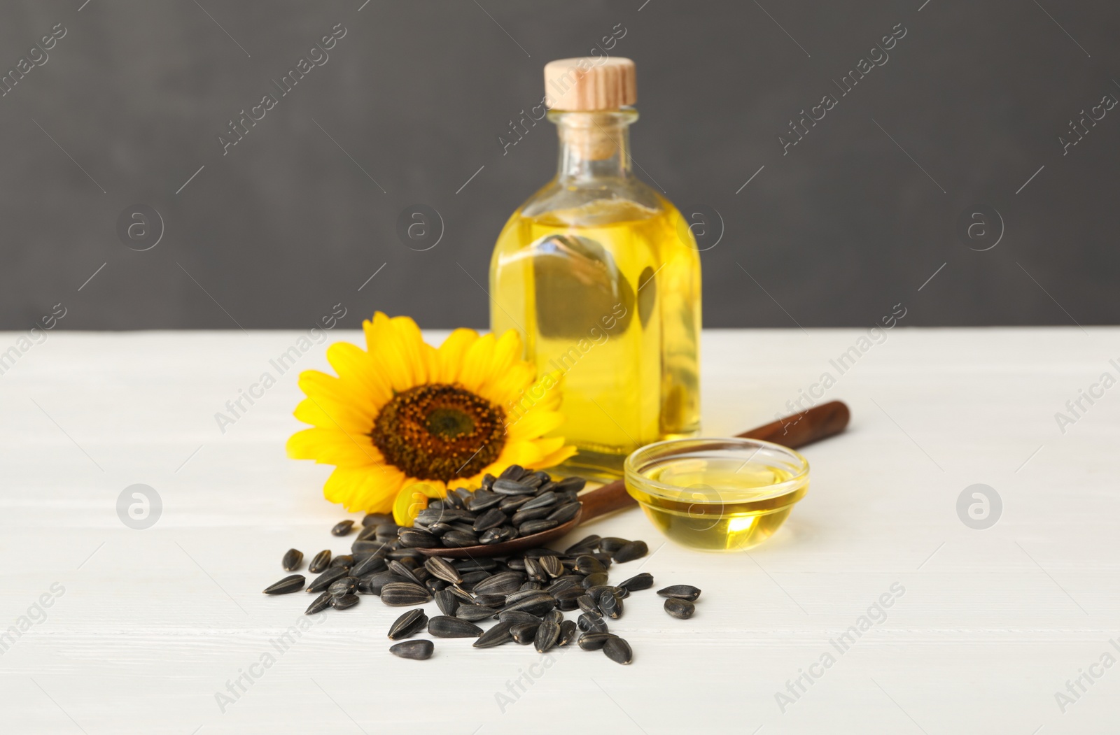 Photo of Sunflower, oil and seeds on white wooden table