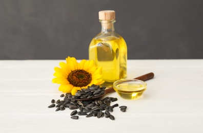 Sunflower, oil and seeds on white wooden table