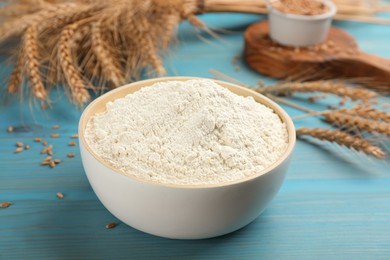 Wheat flour in bowl on light blue wooden table