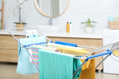 Clean laundry hanging on drying rack in bathroom