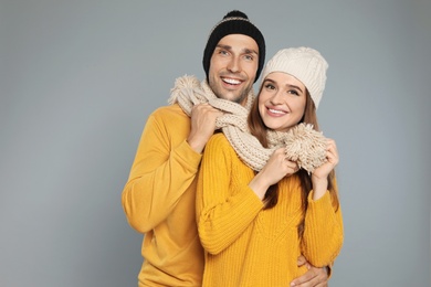 Photo of Happy young couple in warm clothes on grey background. Winter season
