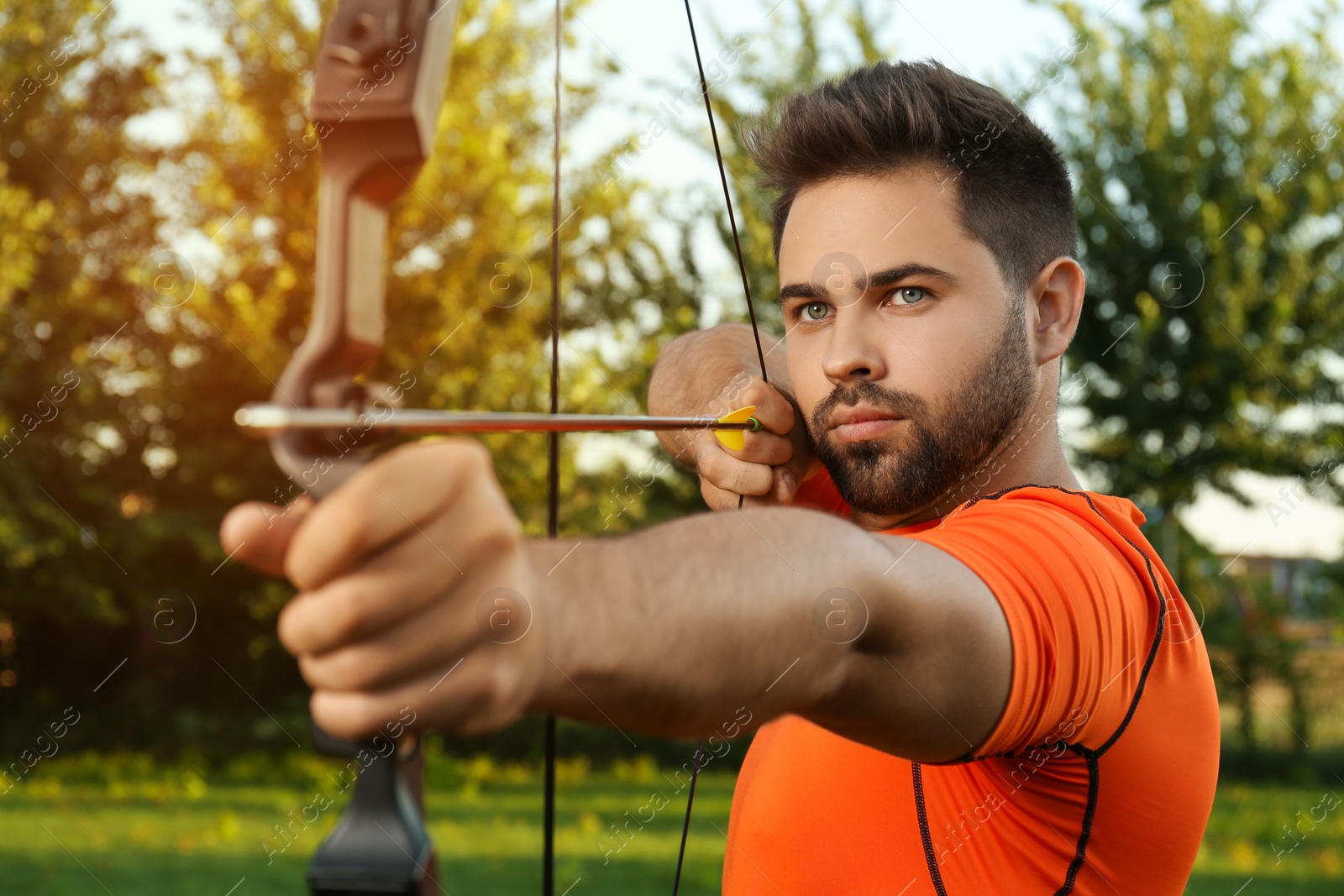 Photo of Man with bow and arrow practicing archery in park