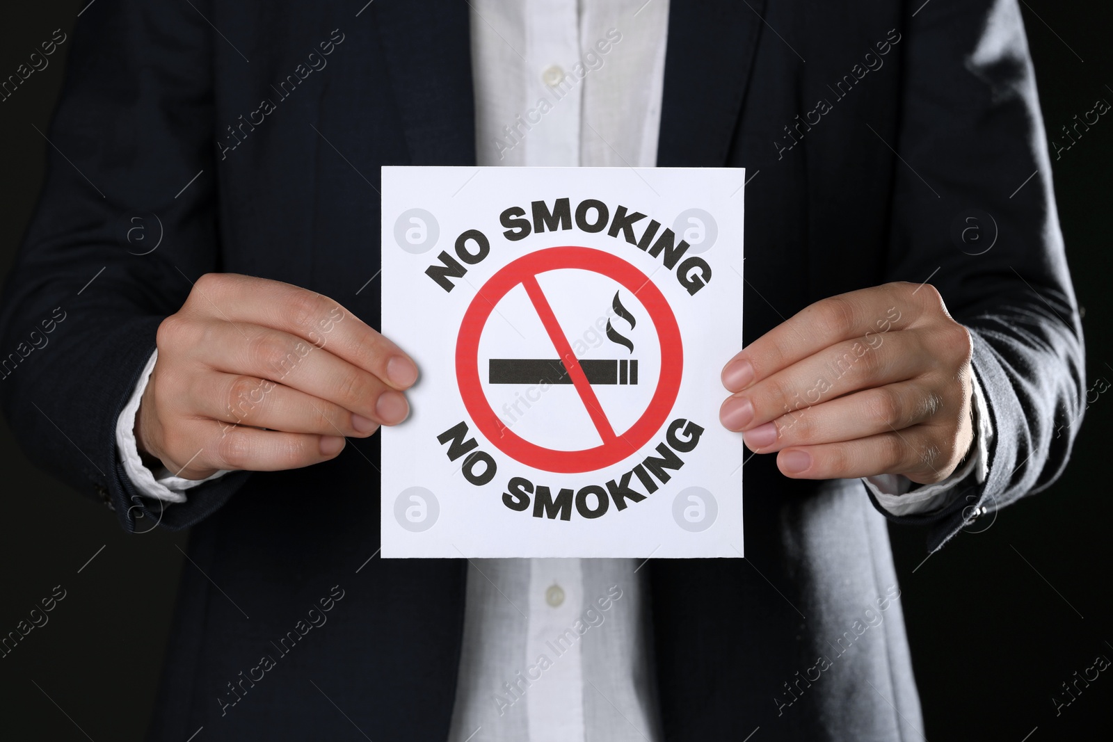 Photo of Woman holding card with no smoking sign on black background, closeup