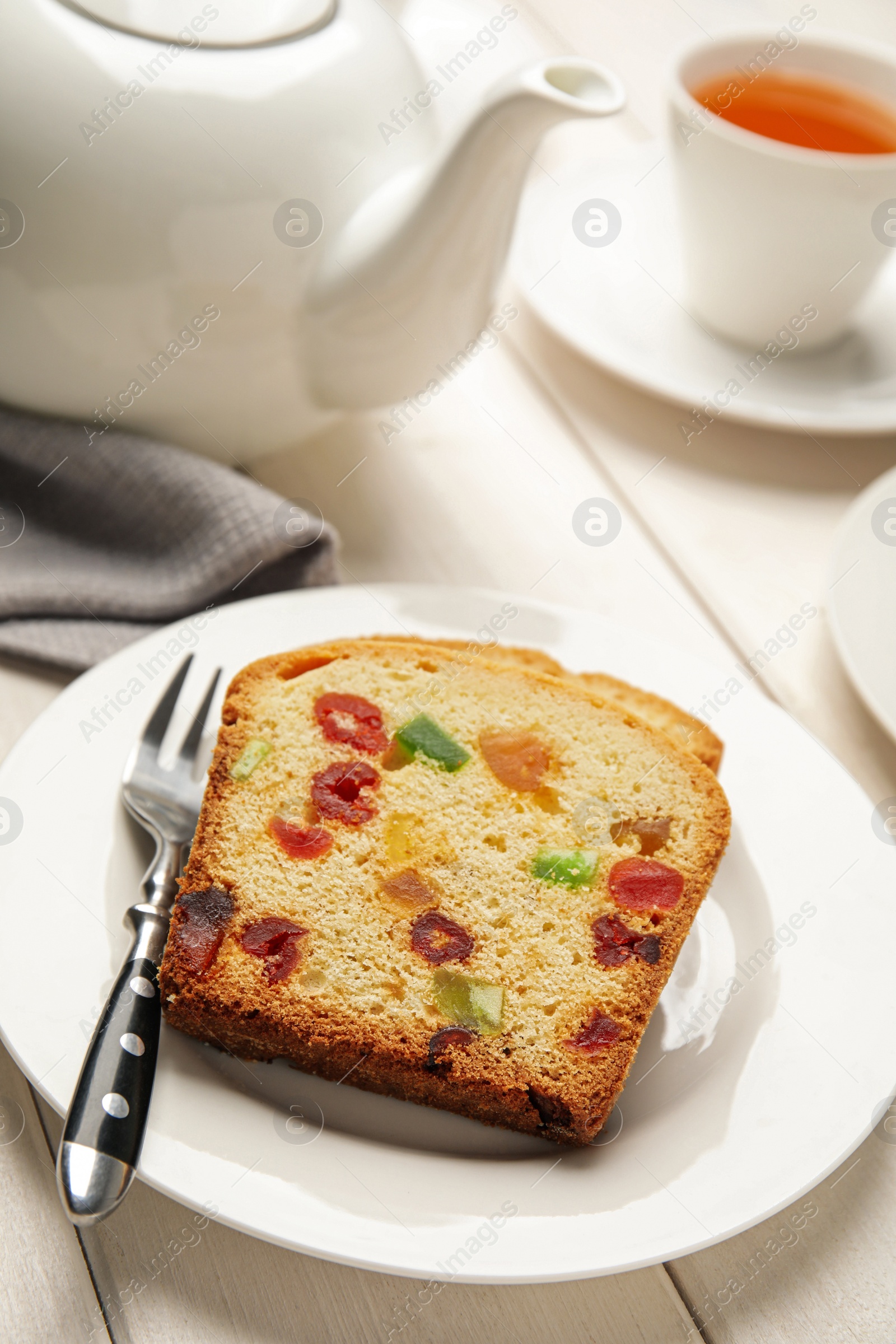 Photo of Delicious cake with candied fruits and tea on white wooden table