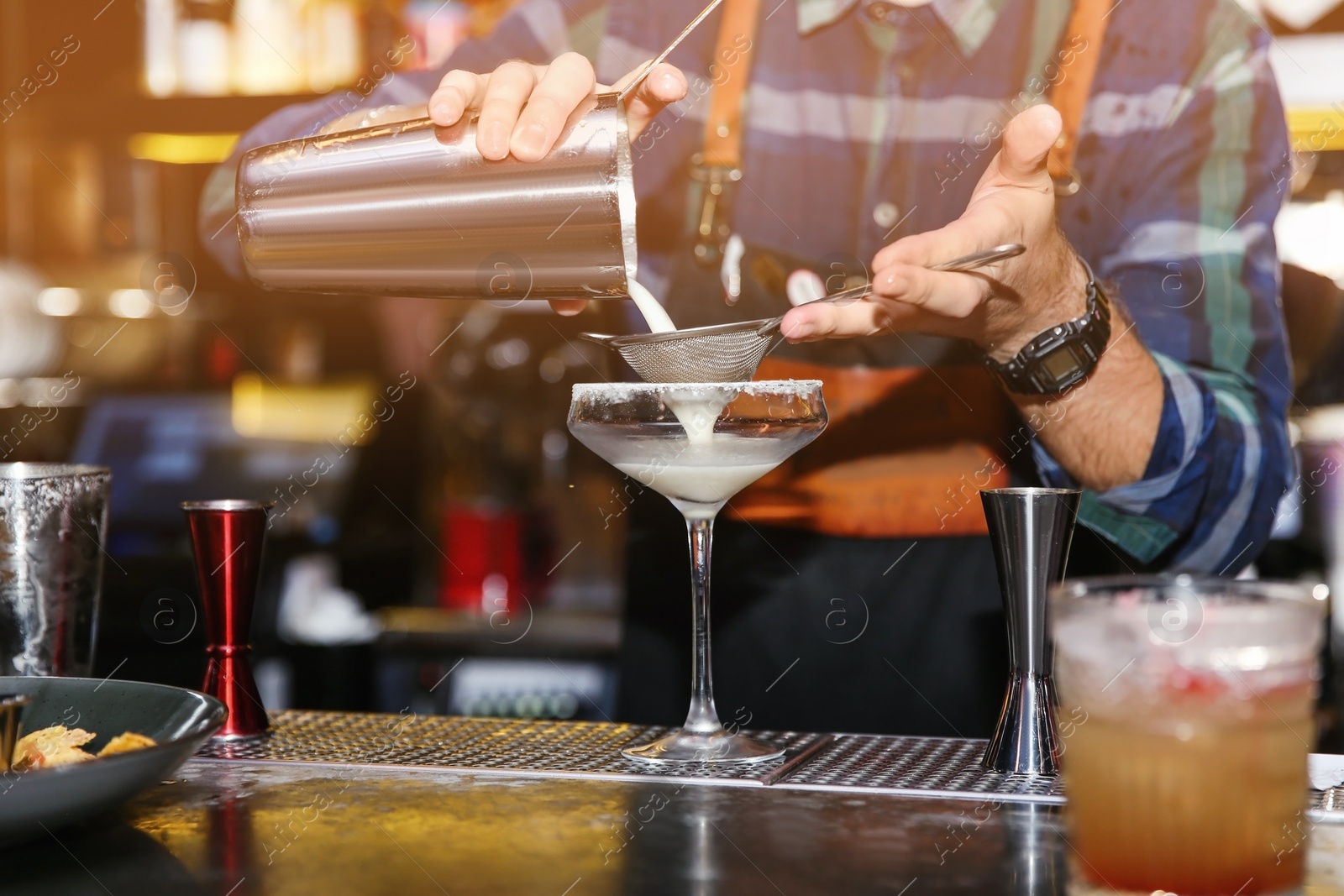 Photo of Bartender pouring tasty cocktail at counter in nightclub, closeup