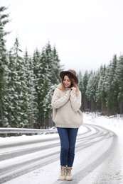 Young woman walking near snowy forest. Winter vacation