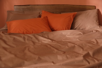 Orange pillows on bed with brown linens