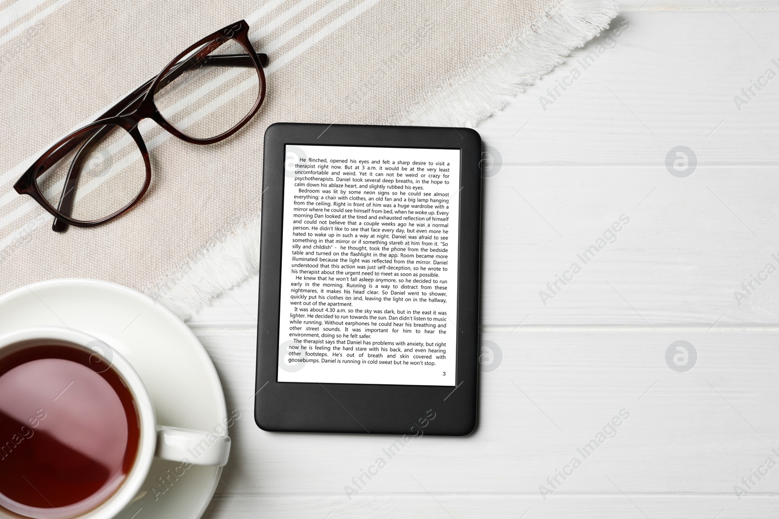 Image of Portable e-book reader, glasses and cup of tea on white wooden table, flat lay. Space for text